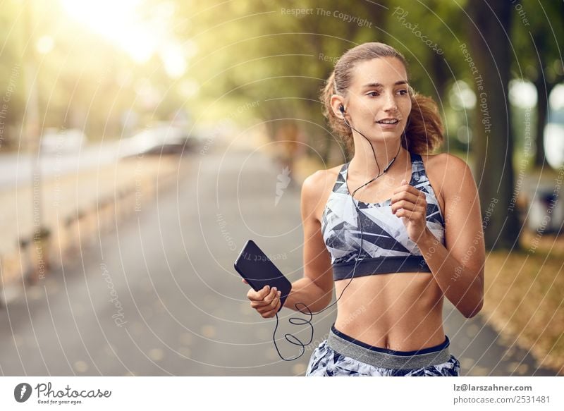 Sporty young woman jogging Lifestyle Summer Music Sports Jogging PDA Woman Adults 1 Human being 18 - 30 years Youth (Young adults) Warmth Park Street Fitness