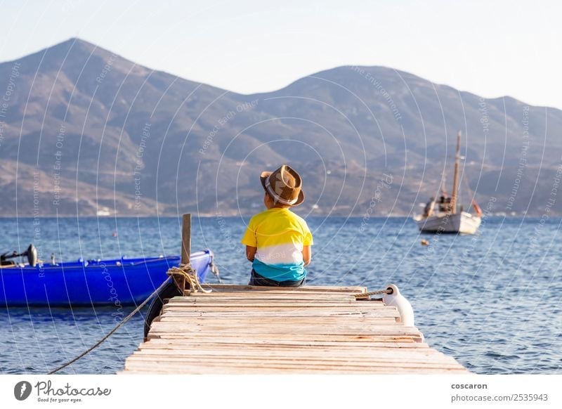 Little boy on a dock sitting on his back looking to the ocean Lifestyle Joy Happy Leisure and hobbies Vacation & Travel Summer Beach Ocean Mountain Child