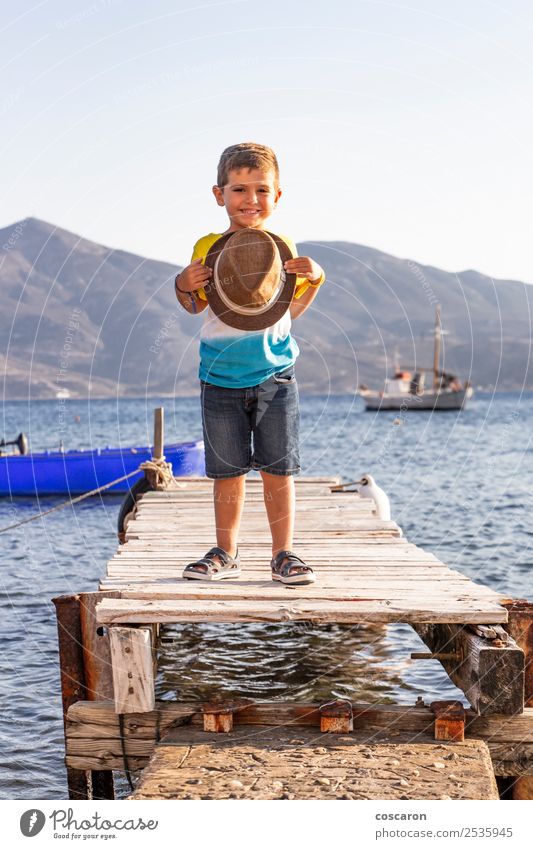 Portrait of a little kid on a dock with a hat in his hands Lifestyle Happy Beautiful Relaxation Leisure and hobbies Vacation & Travel Summer Beach Ocean Child