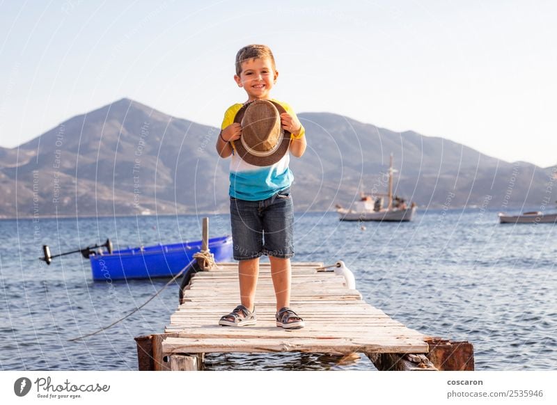 Portrait of a little kid on a dock with a hat in his hands Lifestyle Happy Beautiful Relaxation Leisure and hobbies Vacation & Travel Summer Beach Ocean Child