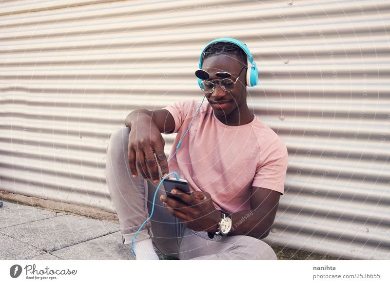 Young man listening to music and use his smartphone Lifestyle Style Design Joy Leisure and hobbies Freedom Cellphone Headset PDA Headphones Technology