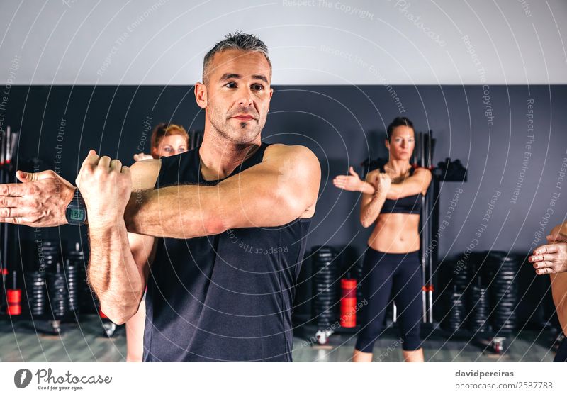 Man stretching his arms in fitness class Lifestyle Happy Beautiful Body Club Disco Sports School Woman Adults Arm Hand Group Fitness Authentic Muscular Practice