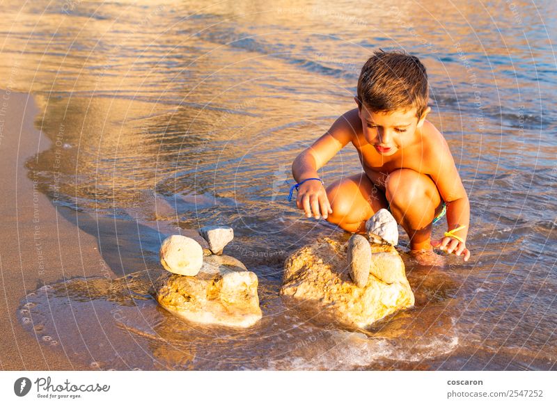 Little kid making constructions with stones on the beach Lifestyle Joy Happy Leisure and hobbies Playing Vacation & Travel Tourism Summer Sun Beach Ocean Child