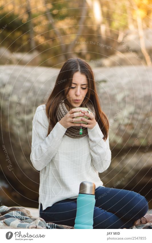 Young woman sitting on the rock drinking tea Food Dairy Products To have a coffee Beverage Hot drink Tea Cup Lifestyle Relaxation Leisure and hobbies