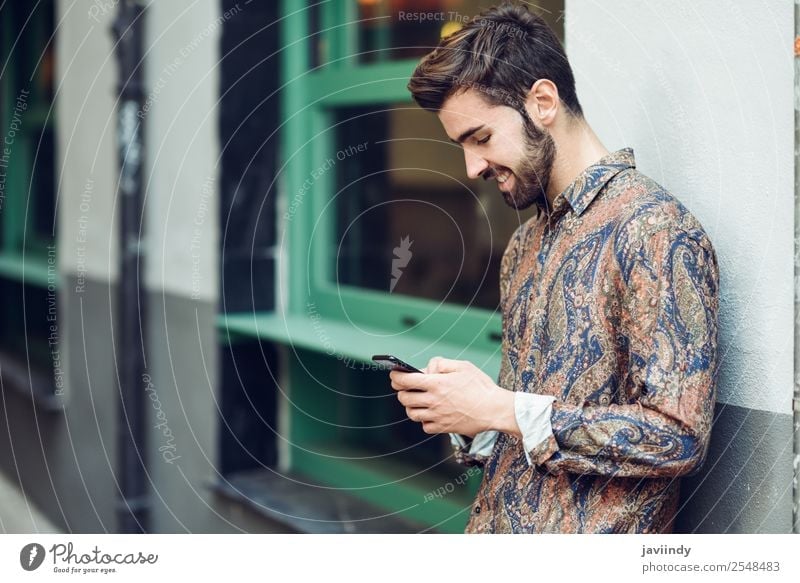 Young smiling man looking at his smartphone in the street Lifestyle Style Beautiful Hair and hairstyles Telephone PDA Human being Masculine Young man