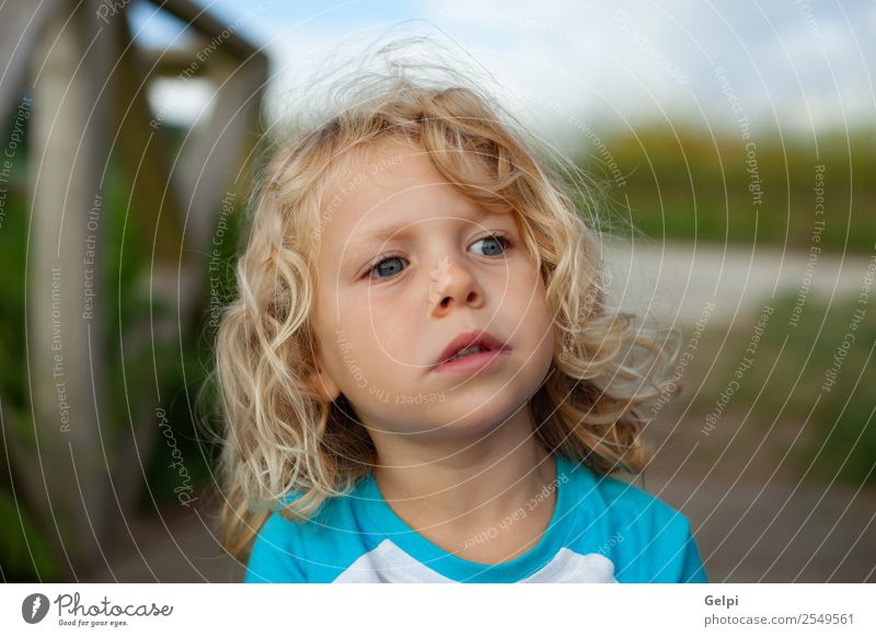 Cute Small Child With Long Hair In The Garden A Royalty Free