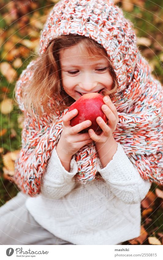 kid girl eating fresh apple in autumn garden Fruit Apple Lifestyle Joy Playing Garden Child Infancy Nature Autumn Warmth Leaf Forest Scarf Smiling Happiness