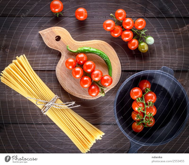 raw spaghetti and red cherry tomatoes Vegetable Dough Baked goods Dinner Pan Table Wood Fresh Yellow Red White pasta food background Raw Spaghetti Tomato