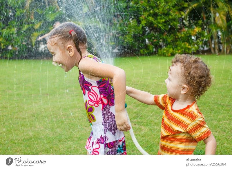 little boy is pouring a water from a hose at her sister Joy Happy Leisure and hobbies Playing Summer House (Residential Structure) Garden Child Human being