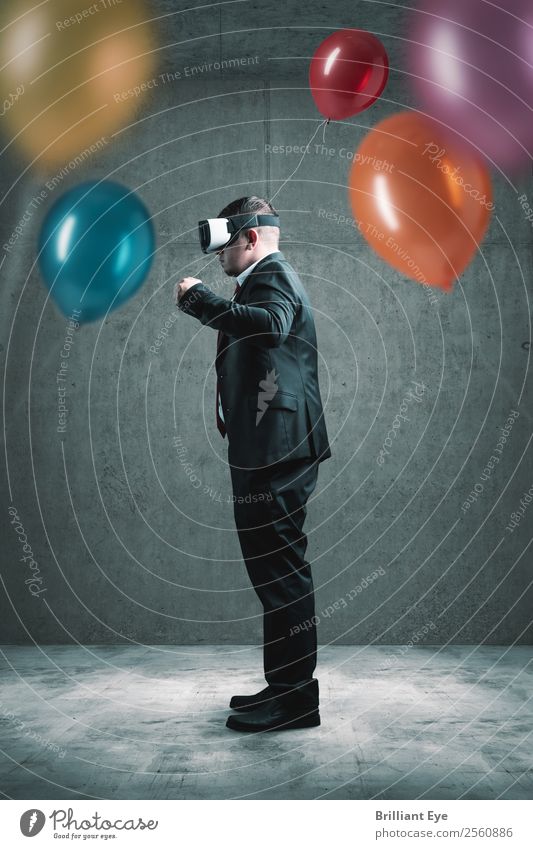 businessman standing with VR headset on concrete floor and holding red balloon in hand in front of lot other colorful balloons Lifestyle Joy Leisure and hobbies