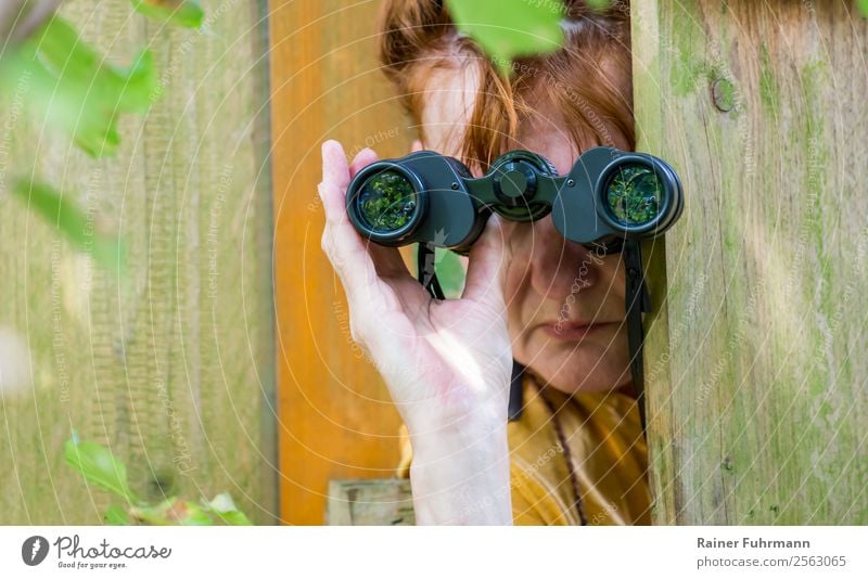 a woman watching through binoculars Human being Feminine Woman Adults Head Hand 1 Nature Garden Red-haired Binoculars Observe Curiosity Interest Revenge