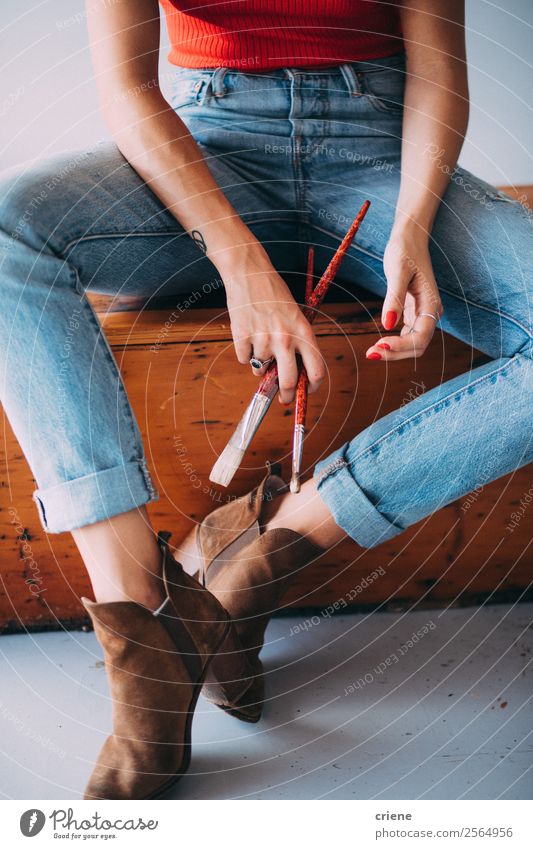close up of female painter sitting on bench holding brushes Elegant Leisure and hobbies Profession Woman Adults Hand Jeans Sweater Boots Love Sit Red Passion