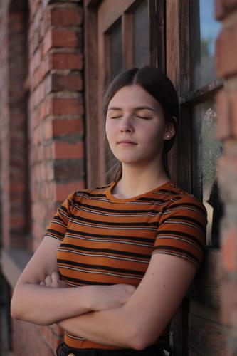 Young woman leaning calmly against brick wall with closed eyes Feminine Youth (Young adults) 1 Human being 13 - 18 years House (Residential Structure)