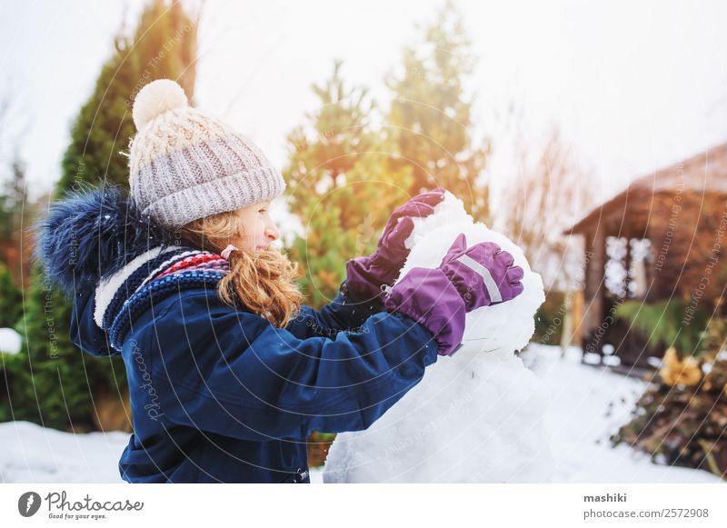 happy kid girl making snow man on Christmas vacations Joy Leisure and hobbies Playing Vacation & Travel Winter Snow Garden Child Nature Weather Park Clothing