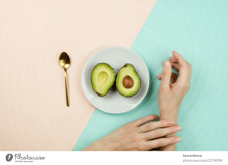 Flatlay with cut avocado on white plate and woman's hands Spoon Vegetarian diet Vegan diet Fruit Eating flat lay Plate Ingredients Diet Healthy Eating