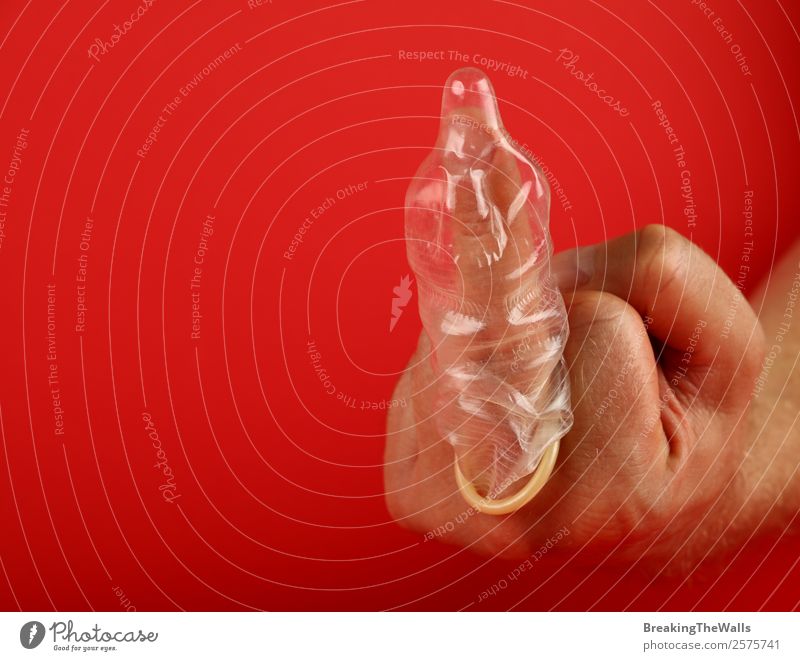 Close up man hand showing condom on finger Healthy Health care Medical treatment Medication Man Adults Hand Fingers Aggression Rebellious Cliche Red Protection