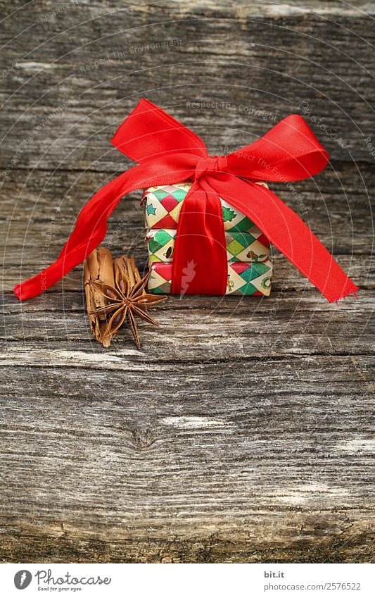 Surprise l colorful Christmas parcels wrapped with Christmas paper with red ribbon, cinnamon, star anise lie on rustic wood. Christmas present, lies nicely decorated with a big bow of red ribbon and christmas spices on a wooden table.