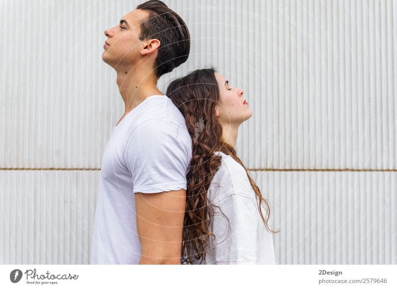 Portrait of a young couple back to back on a white wall Joy Harmonious Summer Human being Woman Adults Man Couple Youth (Young adults) 2 18 - 30 years Street