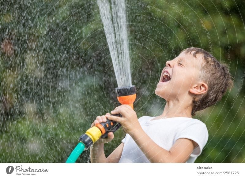 Happy little boy pouring water from a hose. Kid having fun outdoors. Joy Leisure and hobbies Playing Vacation & Travel Freedom Camping Summer