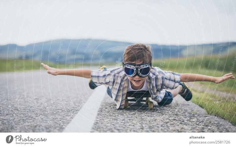 Happy little boy playing on the road at the day time. Kid having fun outdoors. He skateboarding on the road. Concept of sport. Lifestyle Joy Playing