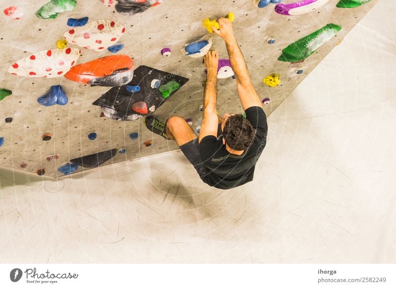 A Man practicing rock climbing on artificial wall indoors. Lifestyle Joy Leisure and hobbies Sports Climbing Mountaineering Young man Youth (Young adults)
