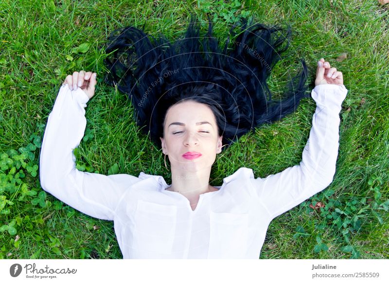 Beautiful brunette is lying on green grass Happy Hair and hairstyles Make-up Woman Adults 18 - 30 years Youth (Young adults) Fashion Brunette Smiling Laughter