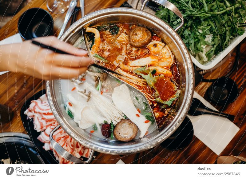 Korean hot pot meal, viewed from top, and one hand taking food from it with chopsticks. Food Meat Vegetable Soup Stew Eating Dinner Asian Food Pot Lifestyle