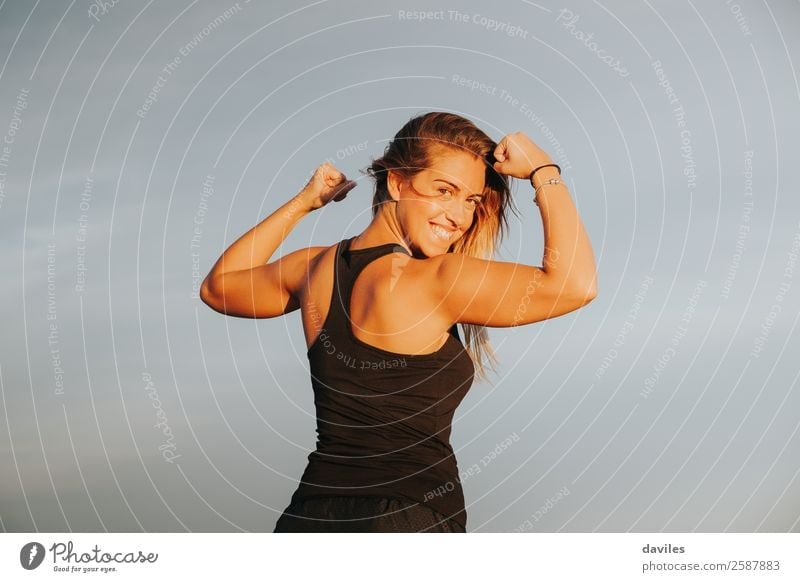 Young girl showing strong biceps after outdoors fitness workout