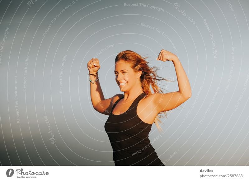 Young girl showing strong biceps after outdoors fitness workout