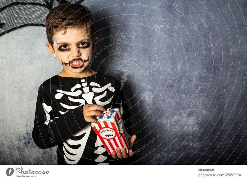 Little kid in a skeleton costume eating fake eyes on Halloween Joy Happy Face Make-up Feasts & Celebrations Carnival Hallowe'en Fairs & Carnivals Child