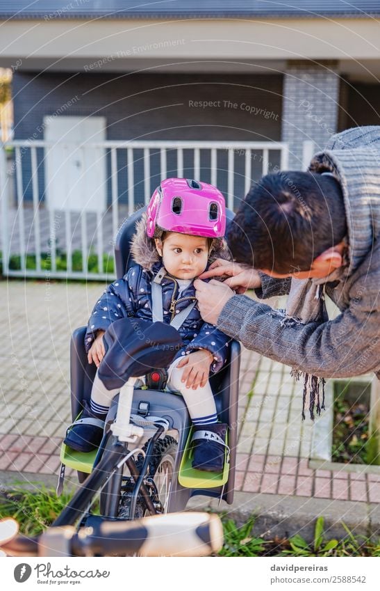 Father closing helmet to her daughter sitting in bike seat Lifestyle Leisure and hobbies Vacation & Travel Trip Chair Cycling Child Baby Toddler Man Adults