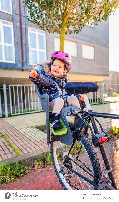 Little girl with security helmet sitting in bike seat Lifestyle Leisure and hobbies Vacation & Travel Trip Chair Sports Child Baby Toddler Woman Adults