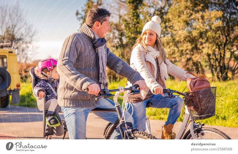 Family with little daughter sitting on bike seat riding bicycles Lifestyle Happy Relaxation Leisure and hobbies Vacation & Travel Sun Winter Sports Child Baby