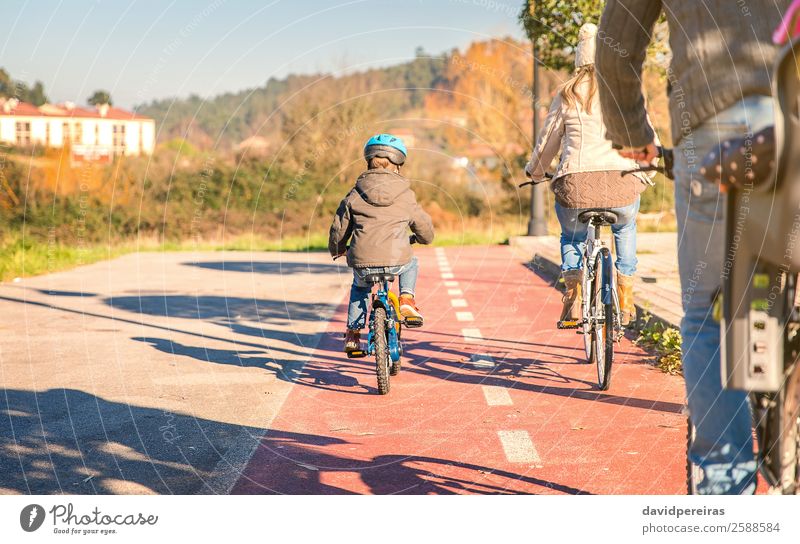 Back view of happy family with children riding bicycles Lifestyle Happy Relaxation Leisure and hobbies Sun Winter Sports Child Baby Boy (child) Woman Adults Man