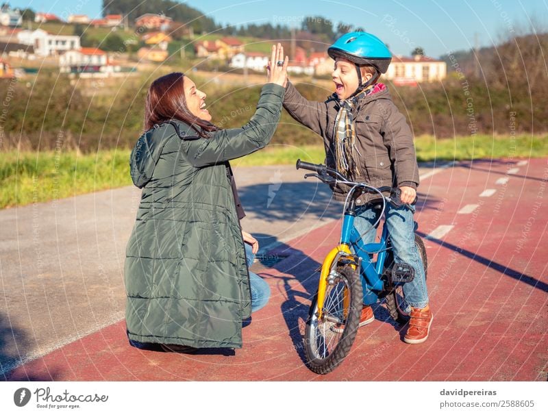 Mother and son giving five in the learn to ride a bicycle Lifestyle Joy Happy Leisure and hobbies Playing Sun Winter Sports Success Cycling Child School