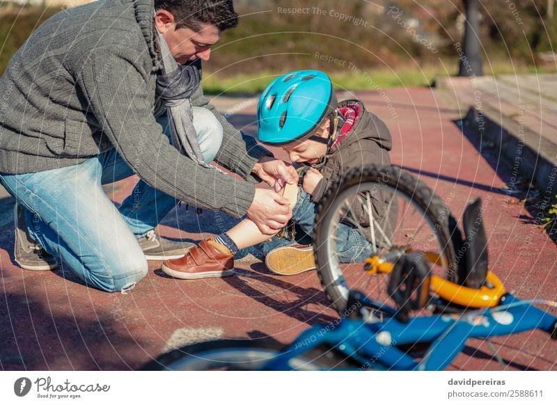 Father putting plaster band over knee injury to his son Medication Sports Child Boy (child) Man Adults Street Lanes & trails Scream Sadness Cry Protection Pain