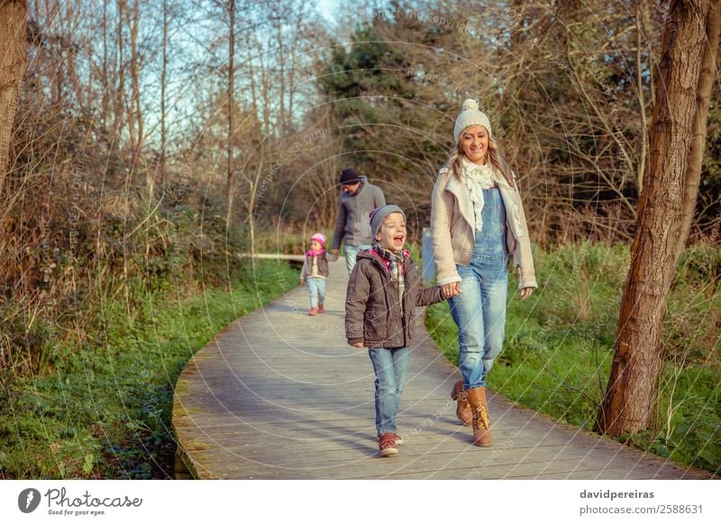 Happy family walking together over a wooden pathway Lifestyle Joy Leisure and hobbies Winter Child Boy (child) Woman Adults Man Parents Mother Father Sister