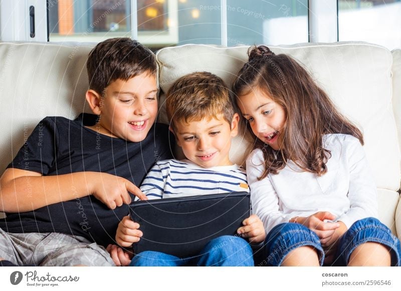 Three kids using a tablet at home Lifestyle Joy Happy Beautiful Leisure and hobbies Playing Sofa Education Child Study Cellphone Computer Notebook Screen