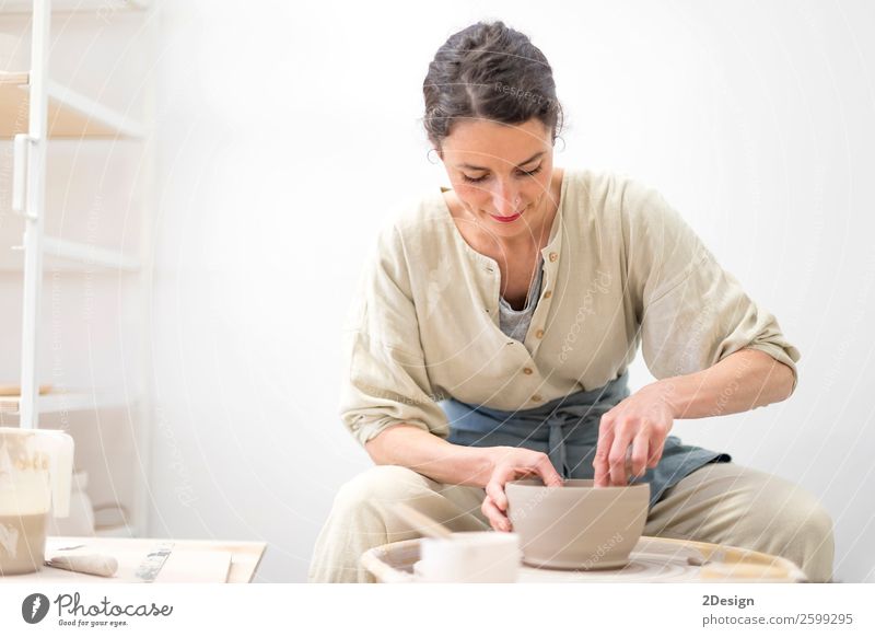 Young female sitting by table and making clay or ceramic mug in her working studio Crockery Leisure and hobbies Handcrafts Table Work and employment Profession