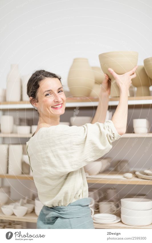 Beautiful ceramist owner looking to the camera while smiling Pot Leisure and hobbies Handcrafts Work and employment Profession Craftsperson Workplace Office