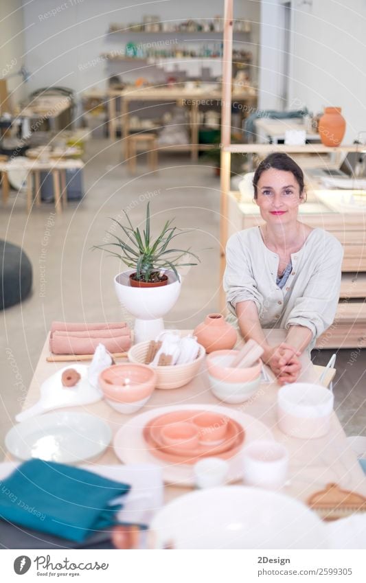 Woman in work wear in her workshop by table with handmade items Crockery Leisure and hobbies Handcrafts Table Work and employment Profession Craftsperson