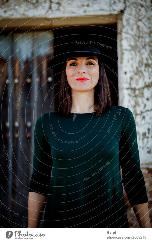 Portrait of an attractive young brunette dark skinned Indian woman in  western black dress holding a cowboy hat in front of her face standing in  white studio background. - a Royalty Free