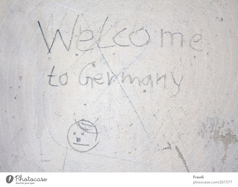 Welcome? Graffiti Small Town Wall (barrier) Wall (building) Facade Sign Characters Communicate Gray Disbelief Mistrust insecurity Colour photo Exterior shot