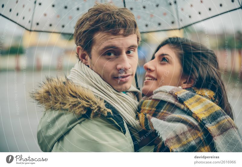 Happy couple embracing outdoors under umbrella in rainy day Lifestyle Beautiful Winter Human being Woman Adults Man Family & Relations Couple Autumn Rain Street