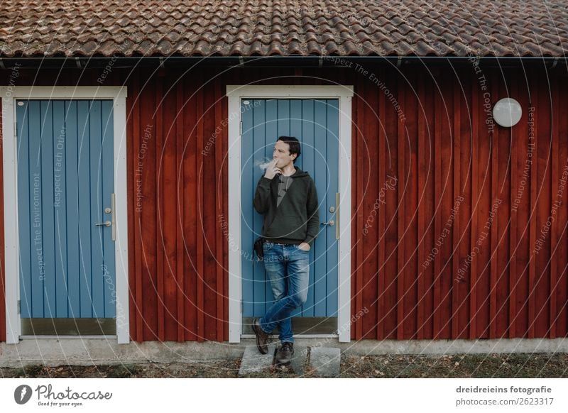 Man stands in front of Schwedenhaus log cabin and smokes cigarette Lifestyle Human being Masculine Adults Hut Smoking Stand Hip & trendy Self-confident