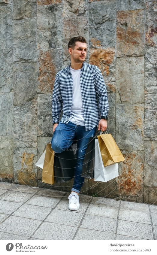 Young man with shopping bags Lifestyle Shopping Hair and hairstyles Relaxation Leisure and hobbies Human being Man Adults Fashion T-shirt Jeans Sneakers Stand