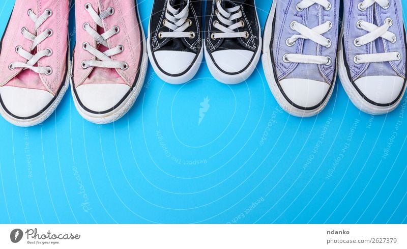 three pairs of textile worn shoes on a blue background - a Royalty