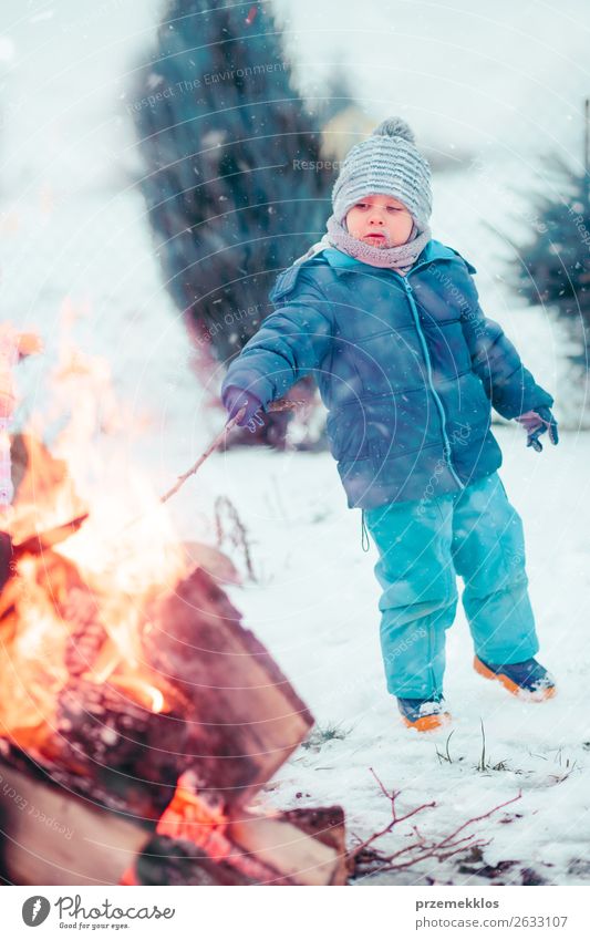 Boy playing a stick by campfire outdoors in the winter Lifestyle Joy Happy Leisure and hobbies Winter Snow Garden Child Human being Boy (child) 1 3 - 8 years