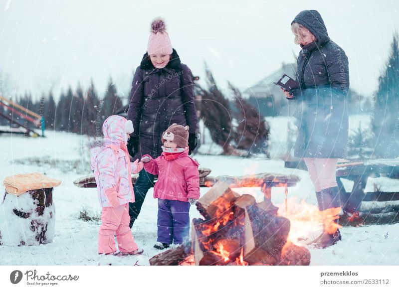 Family spending time together gathered around campfire Lifestyle Joy Happy Leisure and hobbies Winter Snow Winter vacation Garden Child Human being Girl