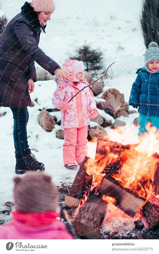 Family spending time together gathered around campfire Lifestyle Joy Happy Leisure and hobbies Winter Snow Winter vacation Garden Child Human being Girl